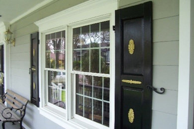 This is an example of a mid-sized traditional front porch design in New York with a roof extension.