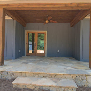 Immagine di un portico stile americano di medie dimensioni e dietro casa con pavimentazioni in pietra naturale e un tetto a sbalzo