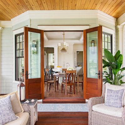 This is an example of a coastal screened-in porch design in Charleston with decking and a roof extension.