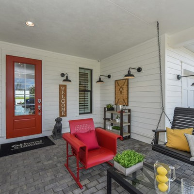 Cottage brick porch photo in Milwaukee with a roof extension