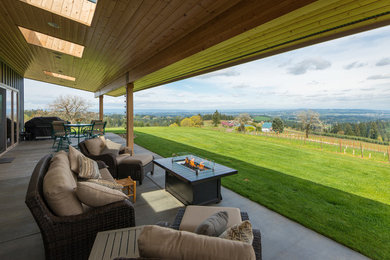 This is an example of a large modern concrete back porch design in Portland with a roof extension.