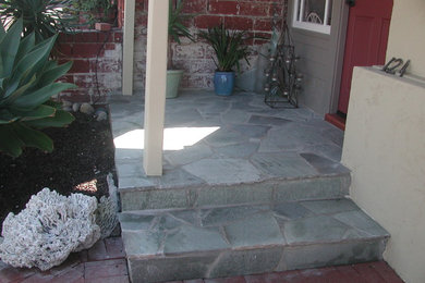 Foto di un piccolo portico stile americano davanti casa con un giardino in vaso, pavimentazioni in pietra naturale e un tetto a sbalzo