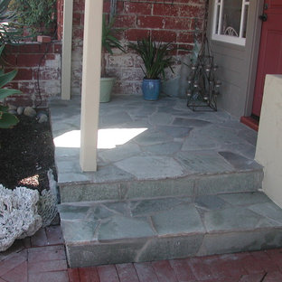 Foto di un piccolo portico stile americano davanti casa con un giardino in vaso, pavimentazioni in pietra naturale e un tetto a sbalzo