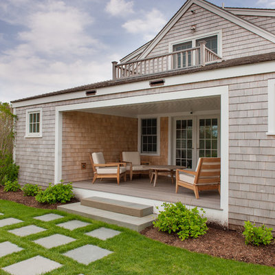 This is an example of a coastal concrete paver back porch design in Boston with a roof extension.