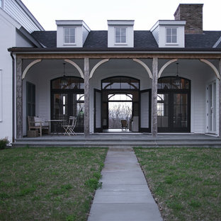 Immagine di un grande portico country davanti casa con pavimentazioni in pietra naturale e un tetto a sbalzo