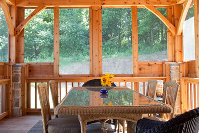 This is an example of a rustic screened-in porch design in Baltimore with decking and a roof extension.