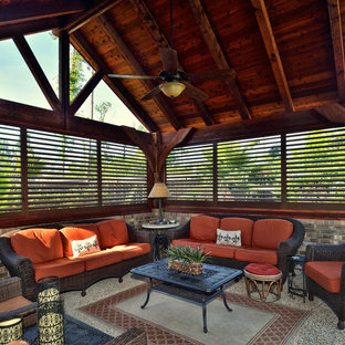 Immagine di un grande portico american style dietro casa con lastre di cemento, un tetto a sbalzo e un portico chiuso