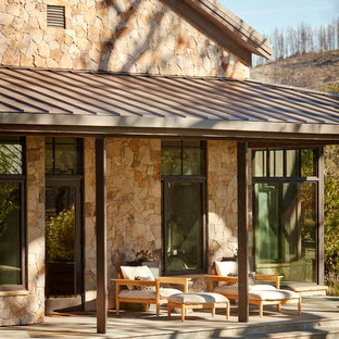 Immagine di un portico country dietro casa con piastrelle e un parasole