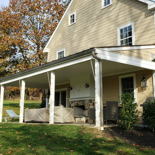 Immagine di un grande portico country dietro casa con un portico chiuso e un parasole