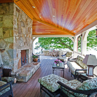 Idee per un portico chic con un focolare, pedane e un tetto a sbalzo