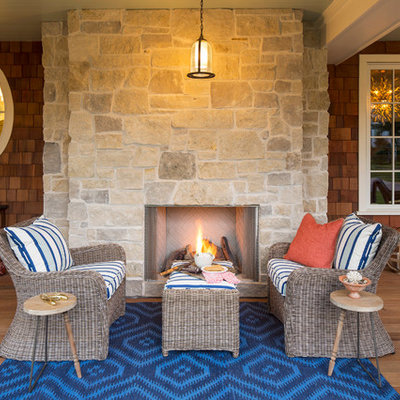 Large beach style front porch photo in Minneapolis with a fire pit and a roof extension