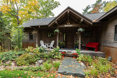 This is an example of a rustic stone front porch design in Other with a roof extension.