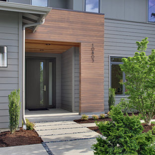 Immagine di un portico design davanti casa con pavimentazioni in cemento e un tetto a sbalzo