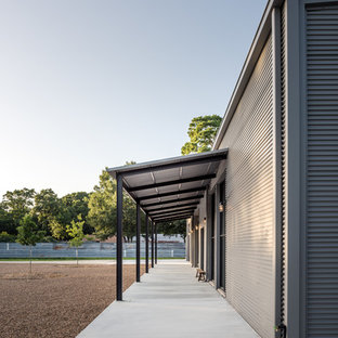 Idee per un grande portico industriale davanti casa con lastre di cemento e un parasole