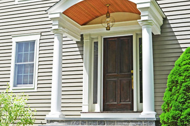 This is an example of a mid-sized traditional stone front porch design in Boston with a roof extension.