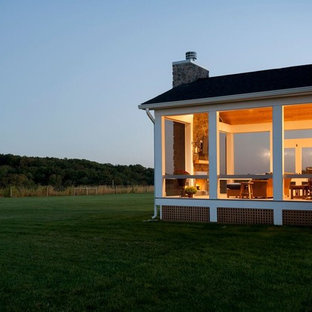 Idee per un grande portico stile rurale dietro casa con un portico chiuso, pedane e un tetto a sbalzo