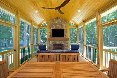 Large transitional screened-in back porch idea in Raleigh with decking and a roof extension