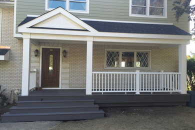This is an example of a mid-sized traditional front porch design in New York with decking and a roof extension.