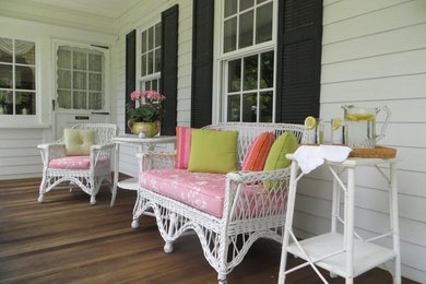 Cette photo montre un porche d'entrée de maison avant chic de taille moyenne avec une terrasse en bois et une extension de toiture.