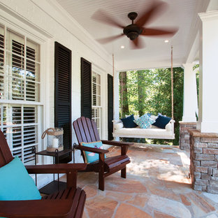 Foto di un grande portico stile americano davanti casa con pavimentazioni in pietra naturale e un tetto a sbalzo