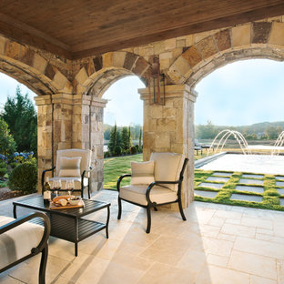 Ispirazione per un portico mediterraneo di medie dimensioni e dietro casa con un portico chiuso, pavimentazioni in pietra naturale e un tetto a sbalzo
