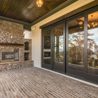 Ispirazione per un portico stile americano di medie dimensioni e dietro casa con un focolare, pavimentazioni in mattoni e un tetto a sbalzo