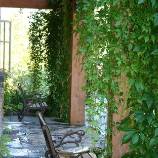Idee per un portico country di medie dimensioni e dietro casa con pavimentazioni in pietra naturale e un parasole