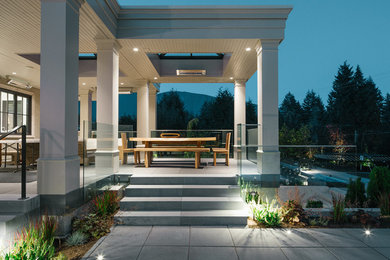 Ejemplo de terraza clásica renovada grande en patio trasero y anexo de casas con adoquines de hormigón