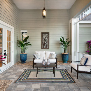 This is an example of a mid-sized tropical stone porch design in Miami with a roof extension.
