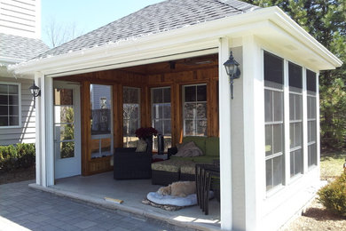 Photo of a medium sized bohemian back screened veranda in Chicago with brick paving and a roof extension.