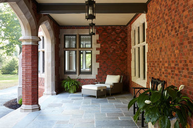 Modelo de terraza clásica renovada de tamaño medio en patio delantero y anexo de casas con suelo de baldosas