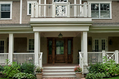 Klassisk inredning av en stor veranda framför huset, med marksten i tegel och takförlängning