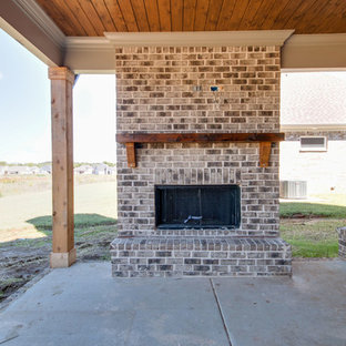 Foto di un portico american style di medie dimensioni e dietro casa con un caminetto, lastre di cemento e un tetto a sbalzo