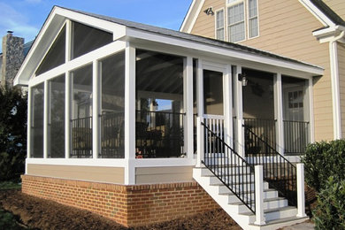 Photo of a medium sized back screened veranda in DC Metro with brick paving and a roof extension.
