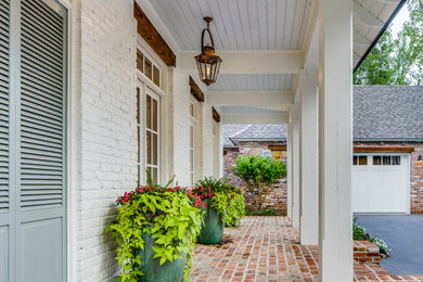 Design ideas for a classic veranda in New Orleans with a potted garden, brick paving and a roof extension.