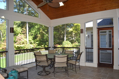 This is an example of a large transitional tile screened-in back porch design in Raleigh with a roof extension.