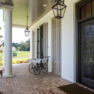 Idee per un ampio portico classico davanti casa con pavimentazioni in mattoni e un tetto a sbalzo