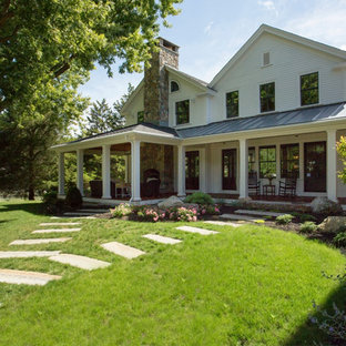 Immagine di un portico country di medie dimensioni e dietro casa con un focolare e un tetto a sbalzo
