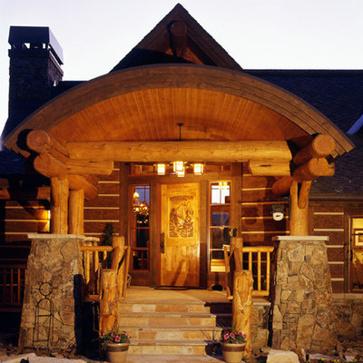 This is an example of a mid-sized rustic stone front porch design in Denver with a roof extension.