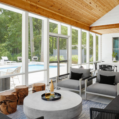 This is an example of a coastal concrete screened-in back porch design in Chicago with a roof extension.