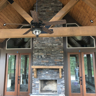 Idee per un grande portico rustico dietro casa con pavimentazioni in mattoni, un tetto a sbalzo e un caminetto