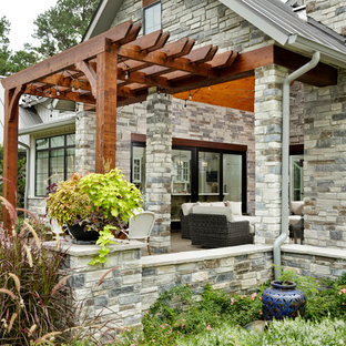 Esempio di un portico country di medie dimensioni e davanti casa con un caminetto, pavimentazioni in cemento e una pergola