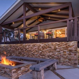 Idee per un grande portico chic nel cortile laterale con un focolare, pedane e un tetto a sbalzo