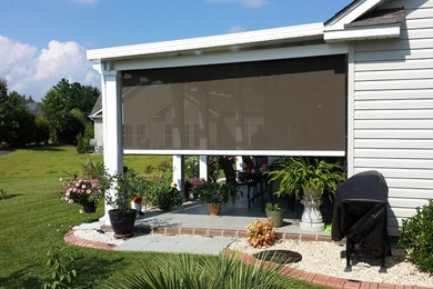 Mid-sized elegant concrete screened-in back porch photo in Other with a roof extension