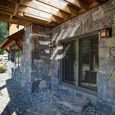 Mid-sized mountain style stone back porch photo in Burlington with a pergola