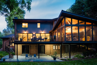 Aménagement d'un grand porche d'entrée de maison arrière contemporain avec une extension de toiture.