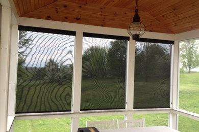 This is an example of a mid-sized traditional screened-in back porch design in Burlington with a roof extension.