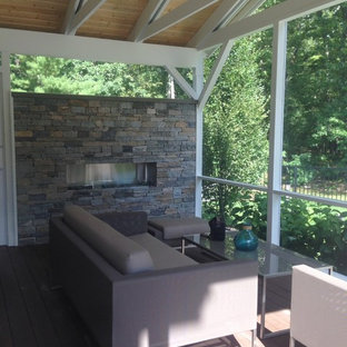 Foto di un piccolo patio o portico minimalista dietro casa con un focolare, pedane e un tetto a sbalzo
