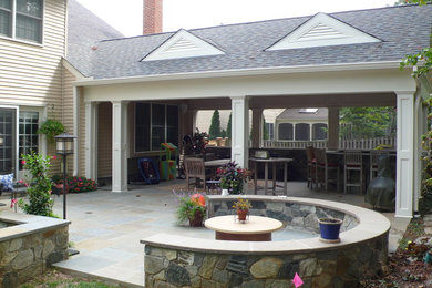 Example of a huge transitional backyard stone patio design in DC Metro with a roof extension