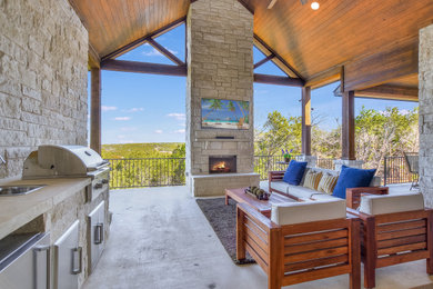 Photo of a large back veranda in Austin with a fireplace, concrete slabs and a roof extension.